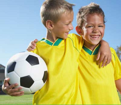 Two boys in uniform with a soccer ball